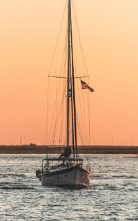 Sailboat sailing on sea against clear sky during sunset