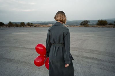 Mid adult woman holding balloon while standing at road