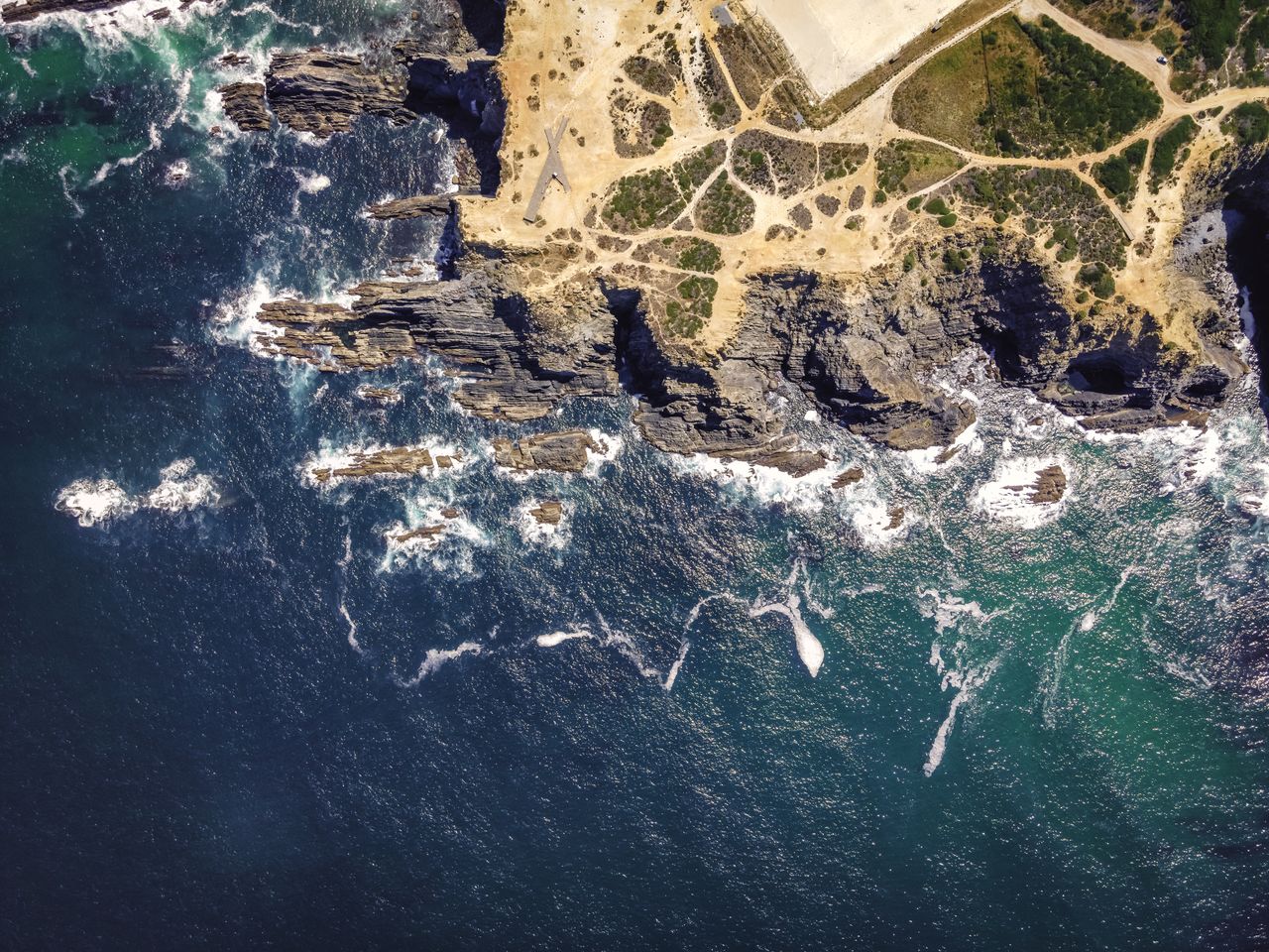 HIGH ANGLE VIEW OF ROCK FORMATIONS ON SEA