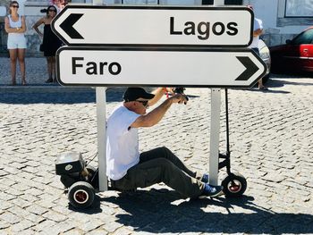 Man sitting on road in city