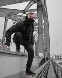 Low angle view of ninja man standing on bridge against sky