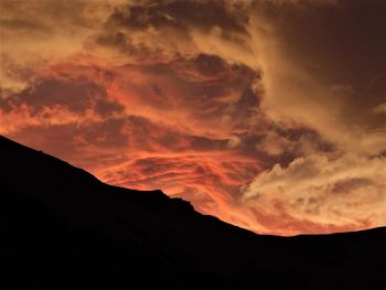 Low angle view of silhouette mountain against dramatic sky