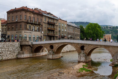 Arch bridge over river against buildings in city