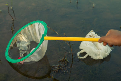 Close-up of hand holding fishing net in water