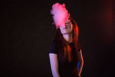 Portrait of a young woman against black background