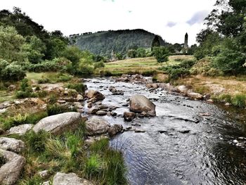 Rocks by stream against sky