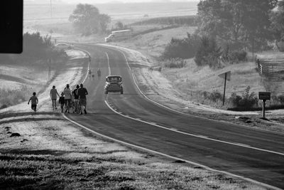 People on road along trees