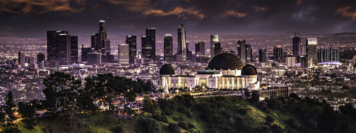 Panoramic view of illuminated buildings against cloudy sky