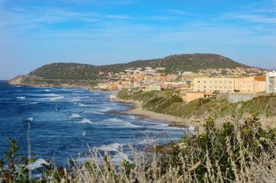 Scenic view of sea and buildings against blue sky