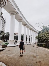 Rear view of man walking on colonnade