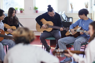 Teenagers attending guitar lesson