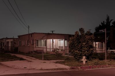 Buildings by street against clear sky at night