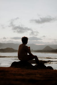 Rear view of man sitting on beach