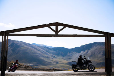 Men riding motorcycles on mountain road against clear sky