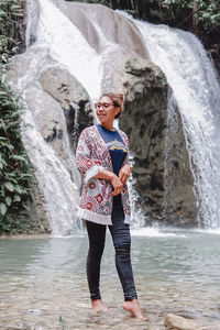 Rear view of woman standing against waterfall