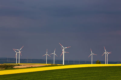 Windmills on field against sky