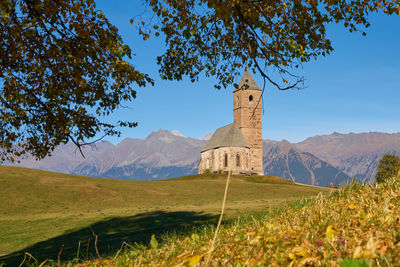 Built structure on field by mountains against sky