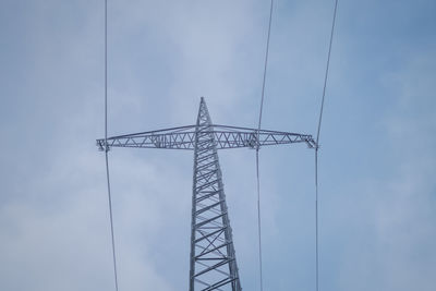 Low angle view of electricity pylon against cloudy sky