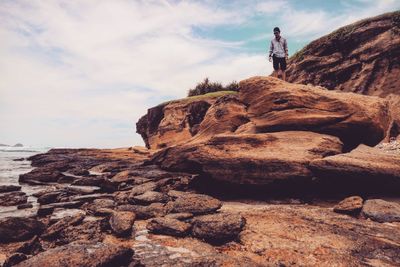 Man standing on rock against sky