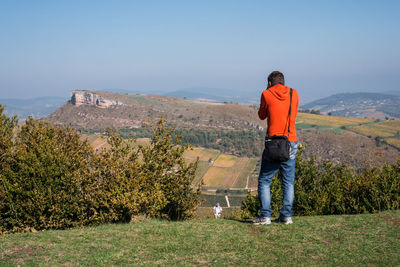 Rear view of young man standing on mountain against clear sky