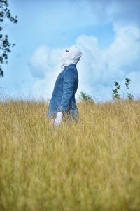 Rear view of person standing on field against sky