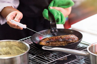 Close-up of person preparing food on barbecue grill