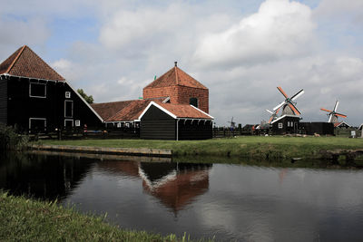 Traditional windmills and houses on field against cloudy sky