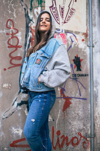 Portrait of woman standing against graffiti wall