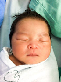 Close-up of cute baby girl sleeping on bed at home