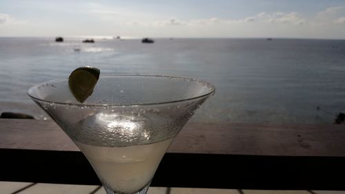 Close-up of beer on beach against sky