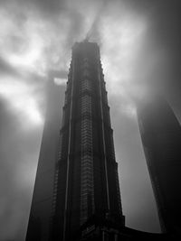 Low angle view of skyscrapers against cloudy sky