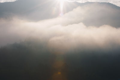 Low angle view of sunlight streaming through clouds