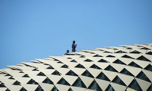 Low angle view of man standing against clear blue sky