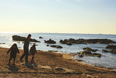 People on beach against clear sky