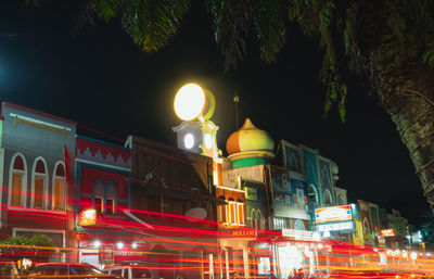 Low angle view of light trails on street against buildings at night