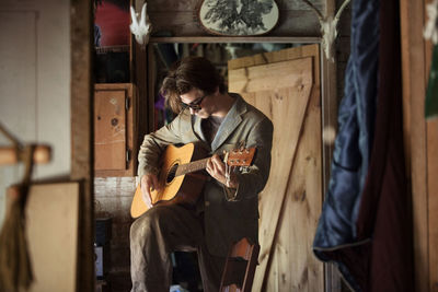 Man playing acoustic guitar while standing at home