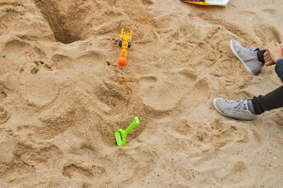 Low section of child playing on sand at beach