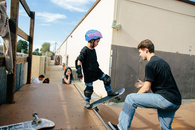 Kid about to go down half pipe with teacher's help