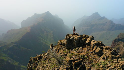 Hiking girl stands on top of the cliff. strength of women. girls power.