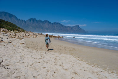 Rear view of woman walking at beach