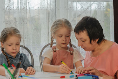 Grandmother assisting granddaughters in drawing