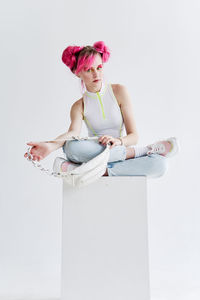 Portrait of young woman sitting against white background