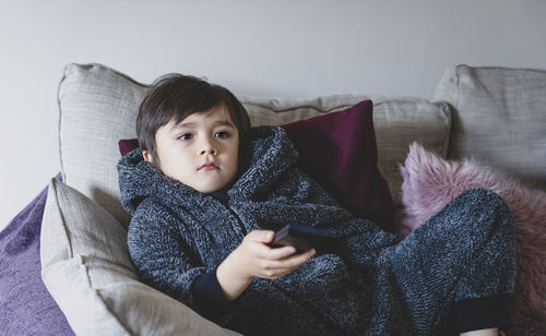 Full length of man using mobile phone while sitting on sofa at home