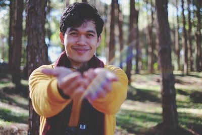 Portrait of smiling young man gesturing in forest