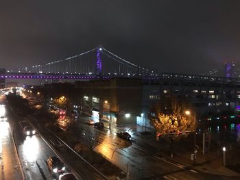 Illuminated bridge over city against sky at night