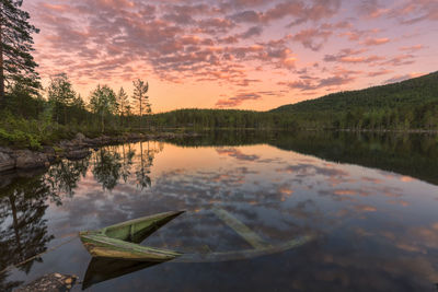 Scenic view sunken canoe in lake at dusk