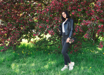 Portrait of young woman by flower on field