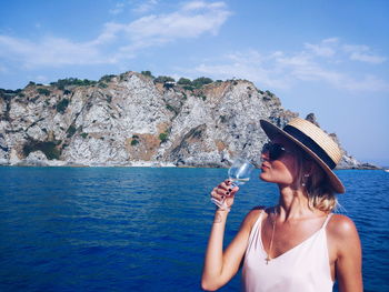 Woman having drink against sky