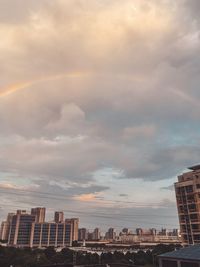 Scenic view of rainbow over buildings in city against sky