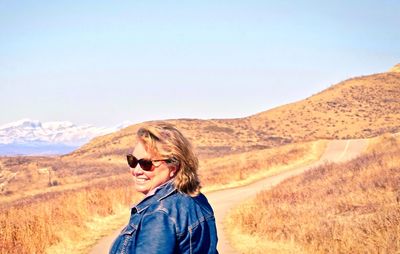 Portrait of smiling woman standing on desert against clear sky